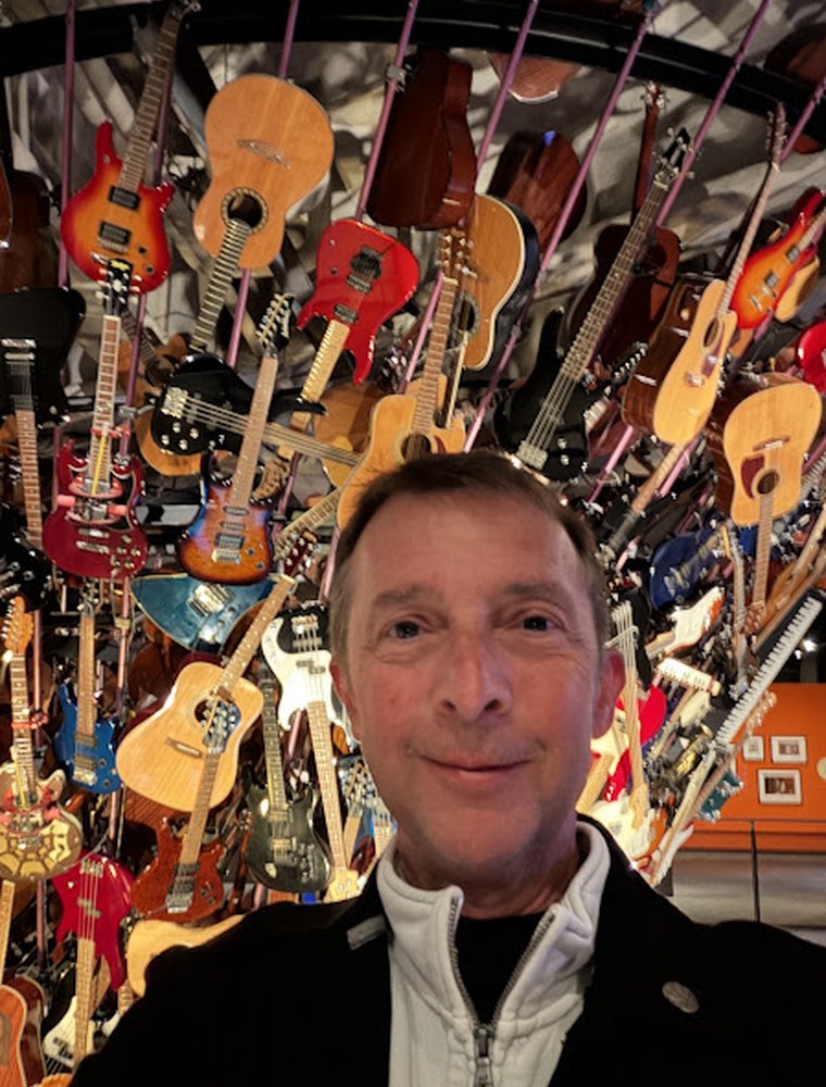 Sean in a room filled with guitars and comic art